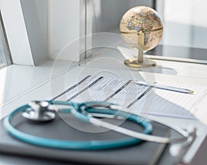 Doctor`s workspace working table with patient`s discharge blank paper form, medical prescription, stethoscope on desk