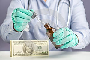 Doctor or Scientist hand holding of cannabis extraction oil bottle with US dollars on the table.