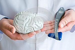 Doctor or scientist holds in one hand figure of brain in another - neurological reflex rubber hammer. Concept photo of neurology,