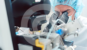 Doctor or scientist looking through microscope in lab