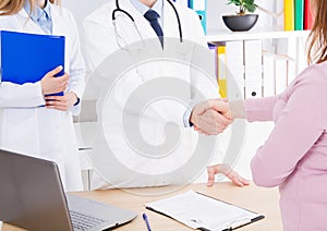 Doctor shakes the female hand his patient in clinic, medical office. Healthcare concept, health insurance