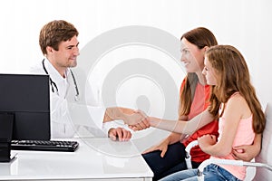 Doctor Shaking Hand With Child Patient In Clinic