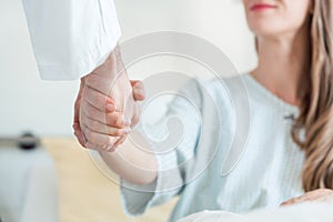 Doctor shaking hand of patient in hospital bed