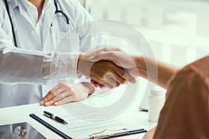 Doctor shaking hands with older patient in the clinic room