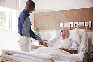 Doctor Shaking Hands With Senior Male Patient In Hospital Bed In Geriatric Unit photo