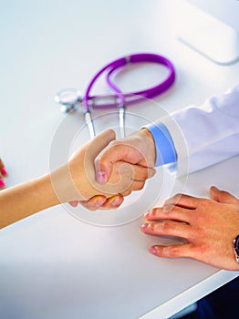 Doctor shaking hands to patient in the office at desk