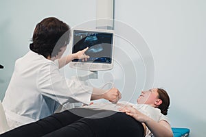 Doctor showing baby ultrasound image on computer to pregnant woman