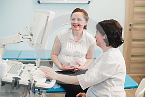 Doctor showing baby ultrasound image on computer to pregnant woman