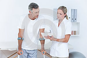 Doctor showing clipboard to her patient with crutch