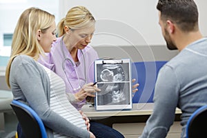 Doctor showing couple scan pictures unborn baby