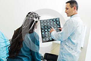 Doctor showing CT scan results to patient undergoing electroencephalography photo