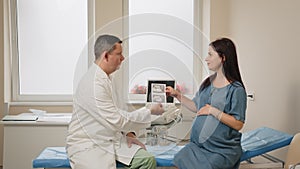 Doctor showing images after ultrasound to pregnant woman