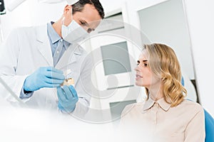 Doctor showing jaws model to female patient in modern