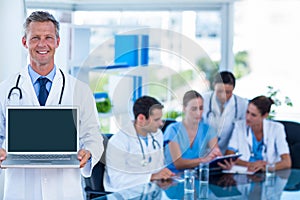 Doctor showing laptop with colleagues behind