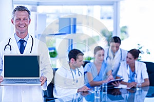 Doctor showing laptop with colleagues behind