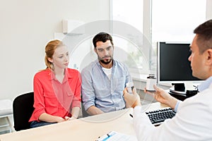 Doctor showing medicine to family couple at clinic