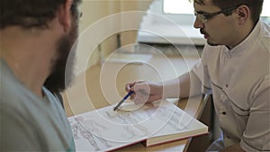 Doctor is showing patient an illustration of human and his acupuncture points.