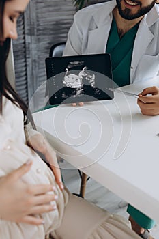 Doctor showing a pregnant girl picture ultrasound. She came to the doctor in the clinic. It's a gynecologist