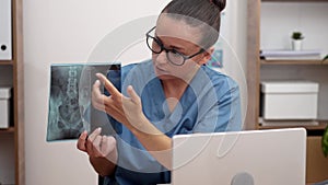 Doctor showing x-ray films to patient in laptop, providing patient with an understanding of disease