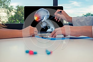 Doctor showing a x-ray of skull with pain in front of the head on a laptop to a woman patient. Headache migraine or trauma concept