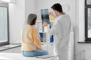 doctor showing x-ray to female patient at hospital