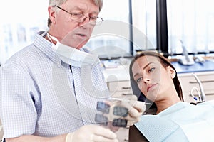 Doctor showing x-ray to female patient. Portrait of mature doctor showing dental x-ray to his female patient.