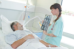 Doctor showing x-ray to patient on bed