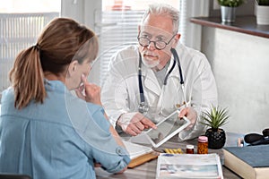 Doctor showing reports on digital tablet to his female patient