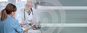 Doctor showing reports on digital tablet to his female patient; panoramic banner