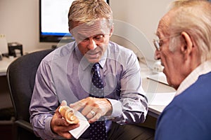 Doctor Showing Senior Male Patient Model Of Human Ear