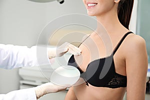 Doctor showing silicone implant for breast augmentation to patient in clinic, closeup.