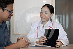doctor showing test result on tablet to patient at hospital. physician talk & give advice to man about his health at medical