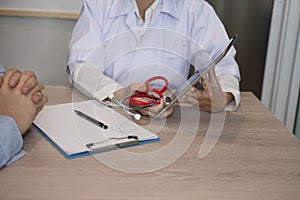 doctor showing test result on tablet to patient at hospital. physician talk & give advice to man about his health at medical