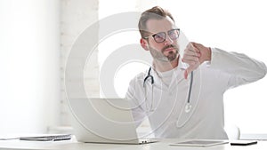 Doctor Showing Thumbs Down Sign While using Laptop in Clinic