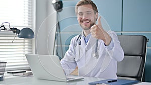 Doctor Showing Thumbs Up Sign While using Laptop at Work