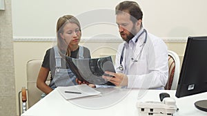 The doctor is showing to the patient her X-Ray