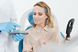 Doctor showing tooth implants to female patient in modern