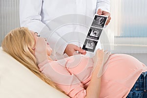 Doctor Showing Ultrasound Scan To Pregnant Woman