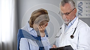 Doctor showing unhappy woman bad test results, cancer treatment, oncology