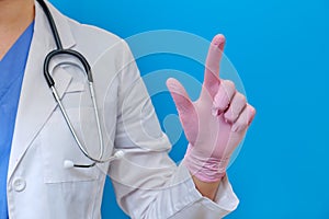 The doctor shows a finger to the side, copy space for text on a blue background. Close-up of a nurse with a stethoscope in pink