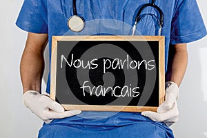 Doctor shows information on blackboard: we speak francais.  Medical concept