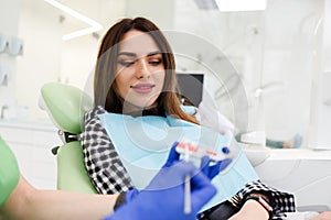 Dentist doctor shows the patient a jaw model and talks about the upcoming treatment.