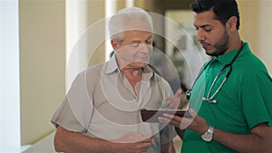 Doctor shows something on his tablet to senior man