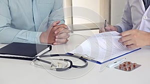 Doctor is signing a medical certificate about the patient`s symptoms at the office