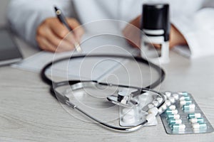 Doctor is signing medical document in office. Stethoscope and stamp on wooden table. Healthcare concept