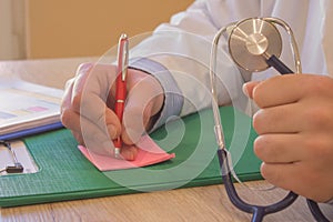 Doctor sits in a medical office in the clinic and writes medical history. Healthcare concept. Medicine doctor`s working table