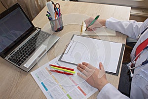 Doctor sits in a medical office in the clinic and writes medical history. Medicine doctor`s working table