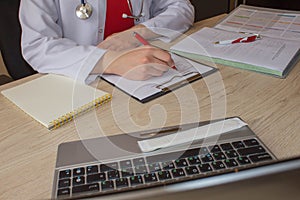 Doctor sits in a medical office in the clinic and writes medical history. Medicine doctor`s working table