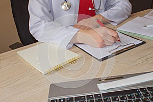 Doctor sits in a medical office in the clinic and writes medical history. Medicine doctor`s working table