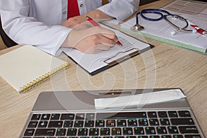 Doctor sits in a medical office in the clinic and writes medical history. Medicine doctor& x27;s working table
